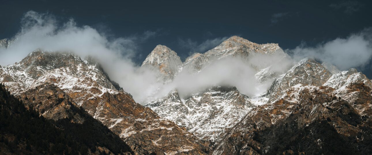 Stunning view of snow-covered Himalayan mountains with clouds and dramatic sky.