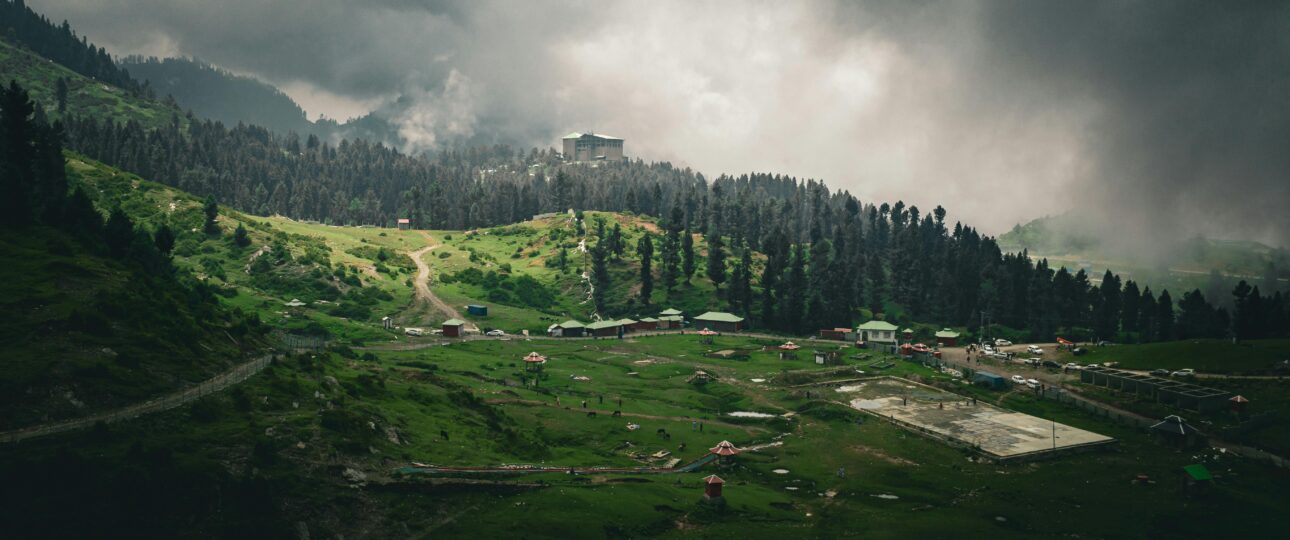 Dramatic view of lush green Malam Jabba landscape with hills and forest under overcast skies.