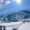 Explore a scenic winter landscape with sunlit snowy mountains and coniferous trees against a bright blue sky.